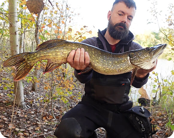 Angler mit Hecht im Herbst